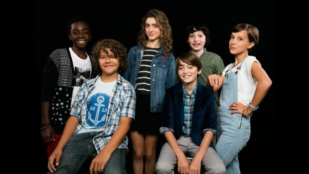 A group of young actors with Gaten Matarazzo smiling against a black background, HD Desktop Wallpaper