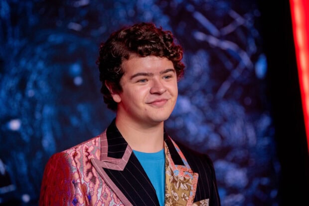 Gaten Matarazzo is smiling wearing a unique patterned blazer against a dark background, 2K Desktop Wallpaper