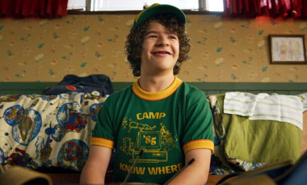 Gaten Matarazzo is smiling while sitting on a bed in a cozy room, HD Desktop Wallpaper