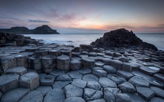 The natural rock columns at Giants Causeway are seen by the ocean under a colorful sky, HD Desktop Wallpaper