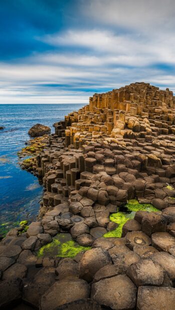 The Giants Causeway shows hexagonal basalt columns along the coast under a cloudy sky, HD Phone Wallpaper