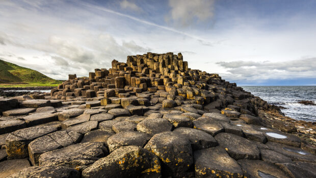 The Giants Causeway rock formations stretch along the coast under a cloudy sky, HD Desktop Wallpaper