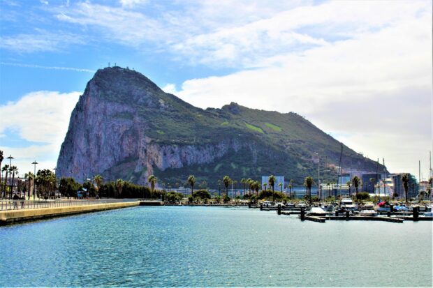 The Gibraltar Rock rises above a marina filled with boats on a sunny day, HD Desktop Wallpaper