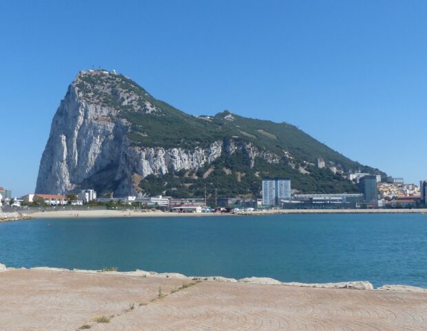 The Gibraltar rock rises above the coastal city with clear blue skies and calm water, HD Desktop Wallpaper