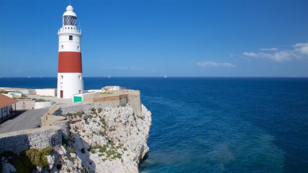 A Gibraltar lighthouse stands tall on rocky cliffs overlooking the deep blue sea, 2K Desktop Wallpaper