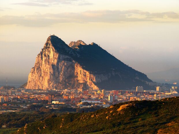 The Gibraltar rock rises prominently above the city under a soft sunset sky, HD Desktop Wallpaper