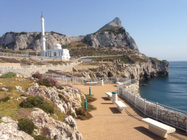 A scenic view of Gibraltar rock and a white mosque near the blue sea under a clear sky, HD Desktop Wallpaper