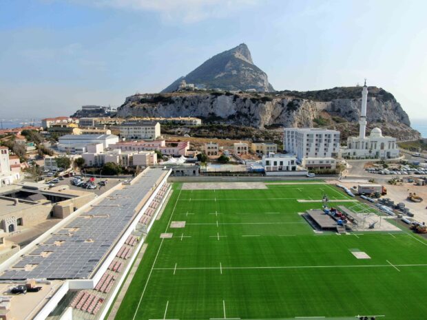 The Gibraltar scenery shows a large green field with buildings and the famous rock in the background, 2K Desktop Wallpaper