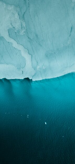 A glacier meeting the deep blue ocean shows natural beauty and calm, 2K Phone Wallpaper