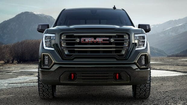 A powerful GMC Sierra truck is shown from the front with mountainous terrain in the background, HD Desktop Wallpaper