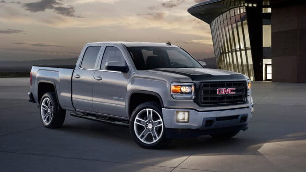 A silver Gmc Sierra pickup truck parked near a modern glass building at sunset, 4K Desktop Wallpaper