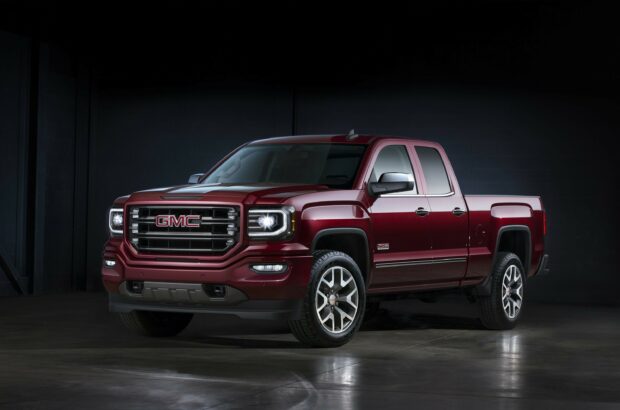 A red GMC Sierra pickup truck parked in a dark garage with lights on, 2K Desktop Wallpaper