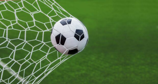 A soccer ball hitting the net during a goal on a green field with clear focus, 2K Desktop Wallpaper