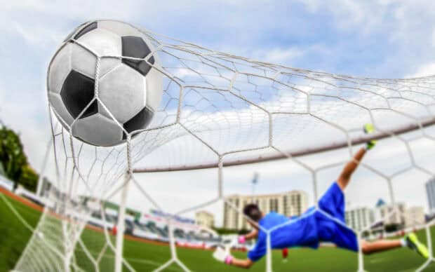 A soccer ball hits the net as the goalkeeper dives, HD Desktop Wallpaper