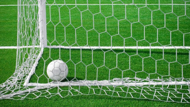 A soccer ball sits inside the net after a goal on the green field, 2K Desktop Wallpaper
