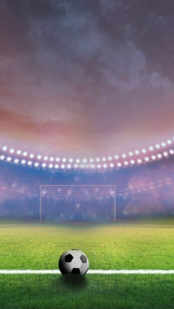 A soccer ball rests on the field with a goal in the background during a sports event, HD Phone Wallpaper