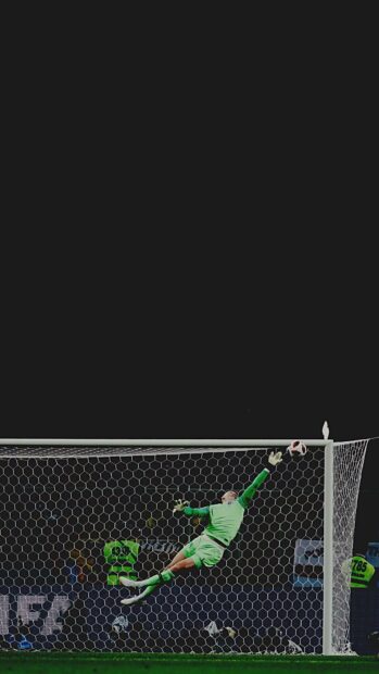 A goalkeeper in a green kit leaps to save a goal during a soccer match, HD Phone Wallpaper