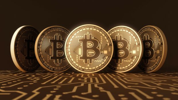 A golden Bitcoin coin stands prominently in front of a row of similar coins on a digital circuit background, HD Desktop Wallpaper
