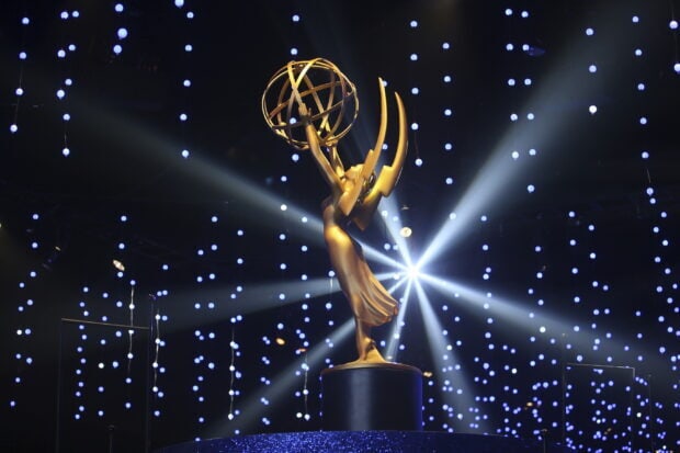 The golden Emmy Awards statue shines brightly with decorative lights in the background, 2K Desktop Wallpaper