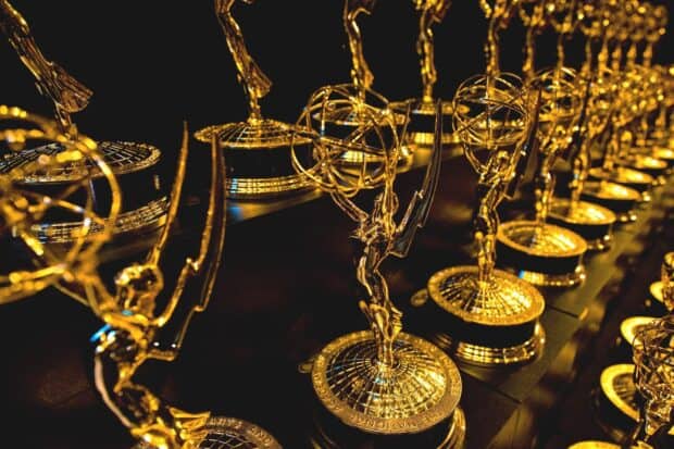 A close up view of golden Emmy Awards trophies aligned in a row on a reflective surface, HD Desktop Wallpaper