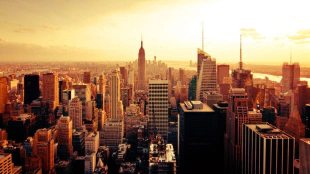 The New York skyline features iconic tall buildings bathed in golden sunset light, 4K Desktop Wallpaper