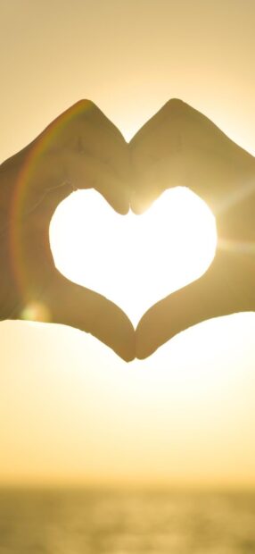 Hands forming a heart shape with sunlight shining through at sunset, HD Phone Wallpaper