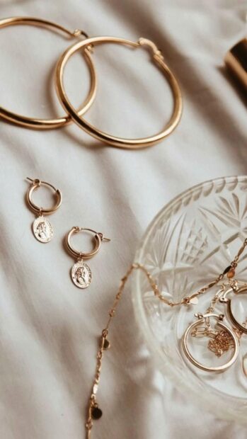 Gold hoop earrings and pendant earrings arranged on a soft fabric, HD Mobile Wallpaper