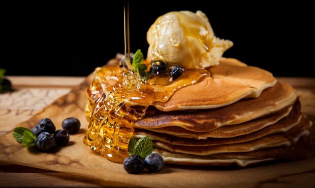 A stack of golden pancakes is topped with melting butter and fresh syrup with blueberries, 2K Desktop Wallpaper