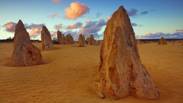The golden rock formations stand tall in Nambung National Park under a partly cloudy sky at sunset, HD Desktop Wallpaper