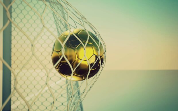 A golden soccer ball is captured just as it enters the goal net in this scene of goal sports wallpapers, 2K Desktop Wallpaper