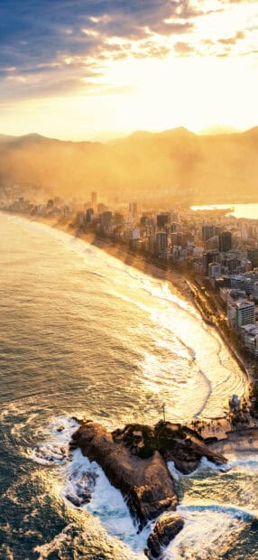 The golden sunset illuminates Rio De Janeiro city along the coastline with mountains in the background, 2K Mobile Wallpaper