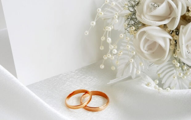 Two golden wedding rings placed beside white roses and delicate pearls on a satin fabric, HD Desktop Wallpaper