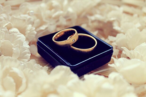 Two golden wedding rings rest on a black box surrounded by delicate white flowers, HD Desktop Wallpaper