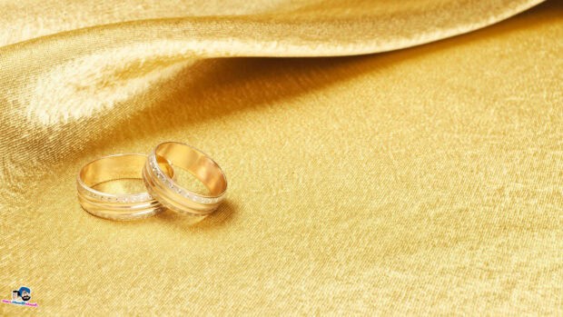 Two golden wedding rings placed on a golden textured fabric, HD Desktop Wallpaper