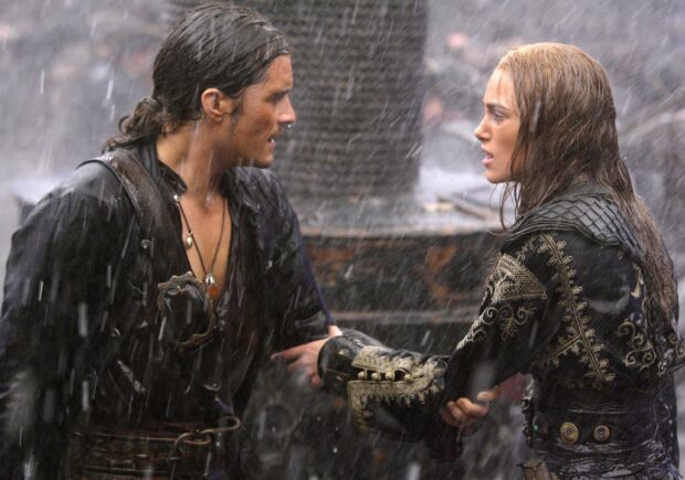A man and woman dressed in pirate attire interact under heavy rain with intense expressions, 2K Desktop Wallpaper