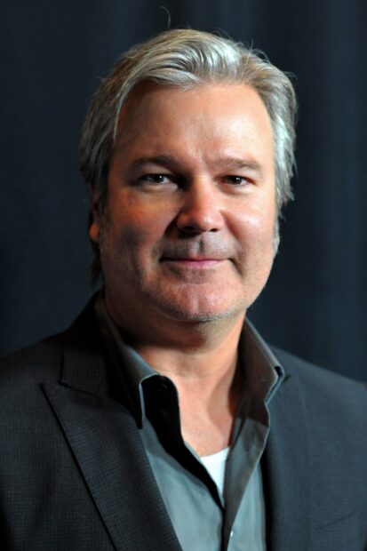 A close up portrait of Gore Verbinski wearing a suit and smiling gently, 2K Phone Wallpaper