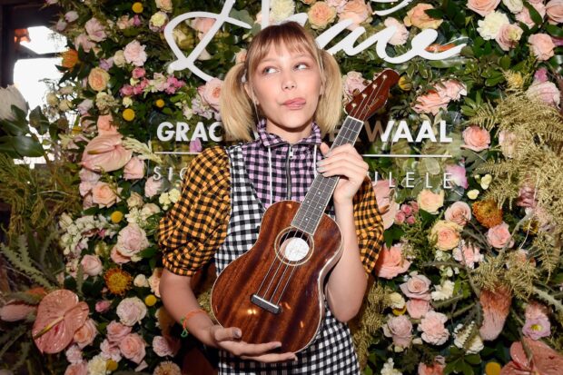 Grace Vanderwaal holding a wooden ukulele in front of a floral background, HD Desktop Wallpaper