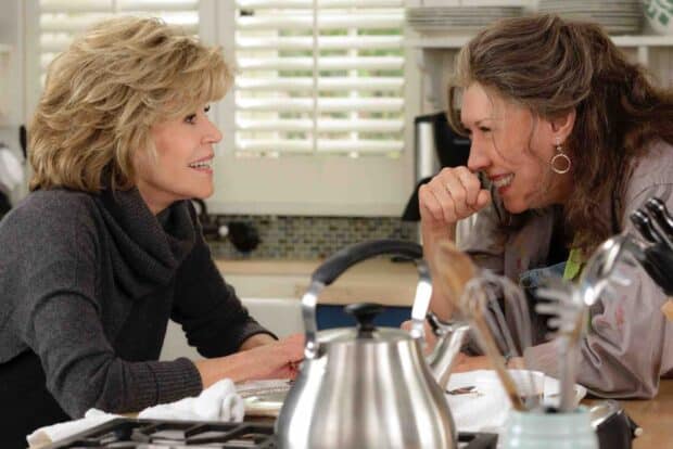 Two women smiling and talking intimately in a kitchen scene from Grace And Frankie Netflix Wallpapers, HD Desktop Wallpaper