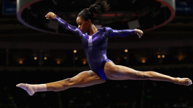 A gymnast performs a split leap during an acrobatic gymnastics event, HD Desktop Wallpaper