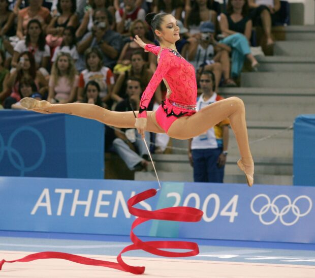 A gymnast performs a leap with a ribbon at a competition, HD Desktop Wallpaper