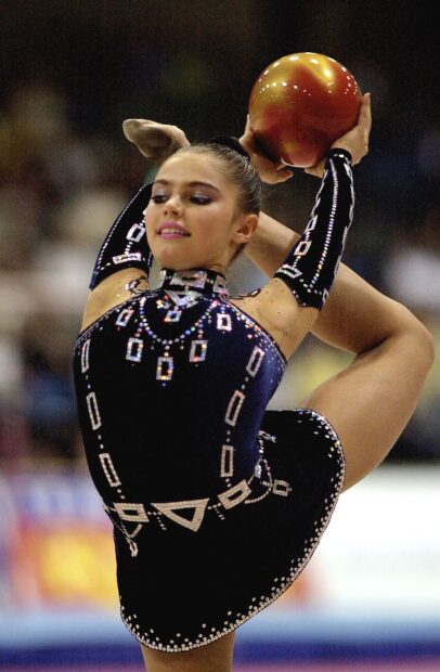 A gymnast performs a balancing pose holding a ball in acrobatic gymnastics, HD Mobile Wallpaper