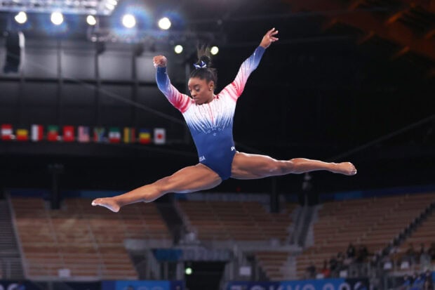 A gymnast performs a split leap during a balance beam routine in competition, 2K Desktop Wallpaper