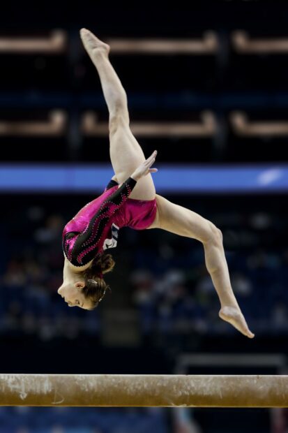 A gymnast performs a skillful move on the balance beam during competition, 2K Phone Wallpaper