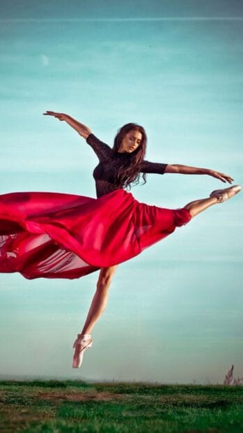 A ballet dancer is captured mid leap wearing a flowing red skirt in an open field, HD Mobile Wallpaper