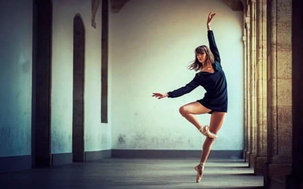 A ballet dancer performs a graceful pose in an architectural hallway showing strength and elegance, HD Desktop Wallpaper