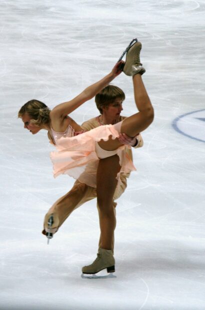 A skilled ice dancing duo performs an elegant lift on the rink during a competition, 2K Phone Wallpaper