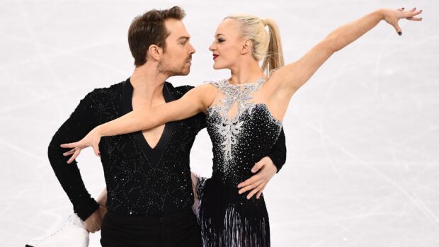 A couple performs a graceful ice dancing routine in matching costumes on the rink, 2K Desktop Wallpaper