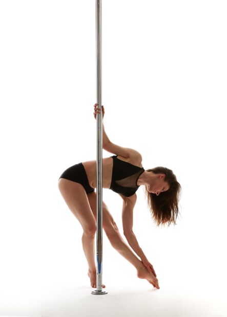 A woman performs a flexible pole dance pose showing strength and balance, 2K Desktop Wallpaper