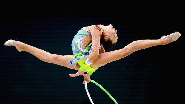 A rhythmic gymnast leaps with a hoop during a performance, 2K Desktop Wallpaper