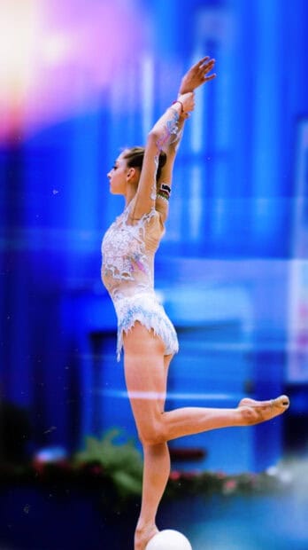 A gymnast performs an elegant pose in rhythmic gymnastics with a ball, 2K Mobile Wallpaper